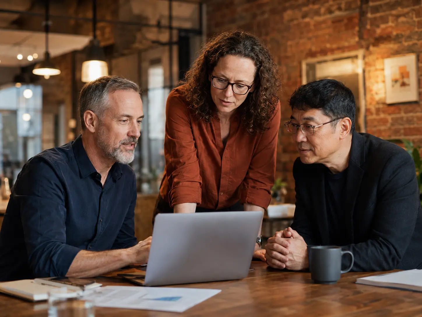 Two men and a woman consultant in office setting looking at a laptop computer
